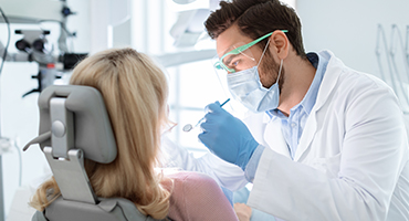 Dentist in mask and gloves doing exam